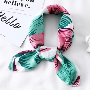 Close-up of a floral silk scarf tied in a bow with elegant leaf patterns and premium texture