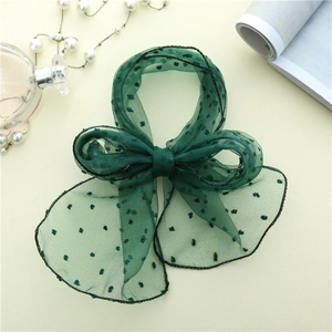 Détail d'un foulard en tulle vert foncé à pois et perles dans un décor chic et élégant
