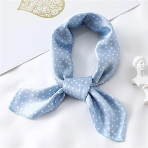 Detail of light blue polka dot silk scarf tied in an elegant knot with a smooth finish
