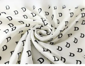 Macro shot of soft white silk scarf with elegant black D-letter pattern and smooth texture