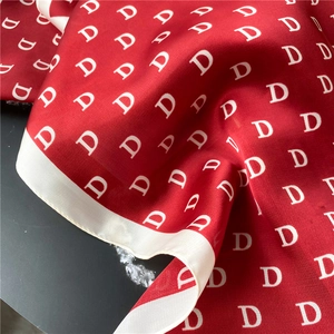 Detail of red satin scarf with white letter D pattern and smooth texture