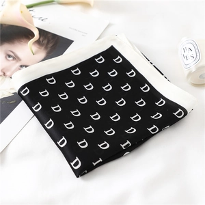 Detail of elegant black and white silk square scarf with all-over D letter pattern