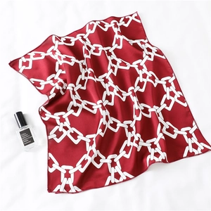 Detail of red square silk scarf with white chain pattern and elegant hand-rolled edges