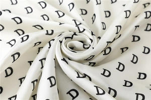 Detail of white silk scarf with black letter D print showing smooth glossy texture