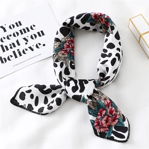 Detail view of a floral silk scarf with animal prints, styled with a lipstick and card