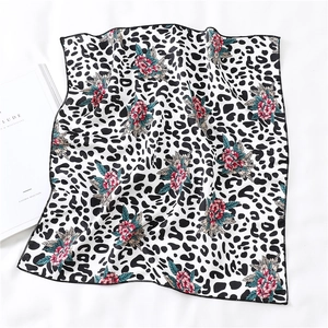Detailed view of leopard print silk scarf with floral pattern and black hemmed edge