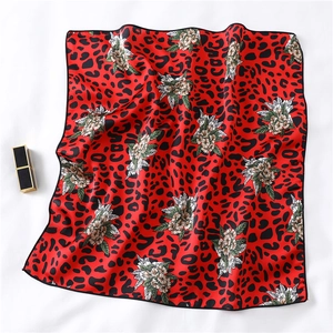 Detailed view of a red silk scarf with black leopard print and white floral patterns