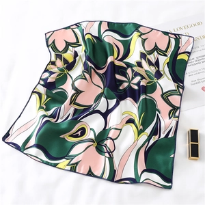 Close-up of pink and green floral silk scarf with dark blue borders on white background