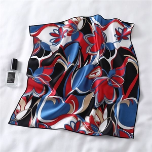 Detail of red and blue abstract floral silk scarf with glossy texture and perfume accessory