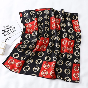 Detailed view of the red and black silk scarf with golden chain patterns and fine hems