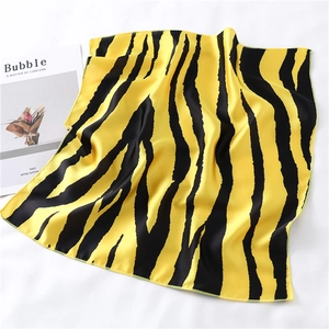 Close-up of yellow tiger print silk scarf with machine-rolled edges on white cloth