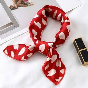 Detail of red silk scarf with white floral print and elegant knotted bow style
