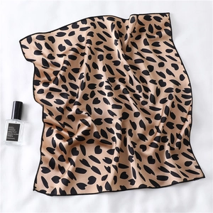 Detail of champagne square silk scarf with black leopard pattern on white fabric
