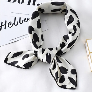 Close-up of elegant black and white polka dot silk scarf tied in a bow on a white surface