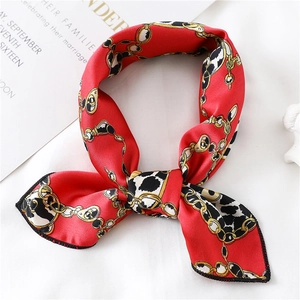 Detail of red silk scarf with golden chain and leopard print tied in a bow knot