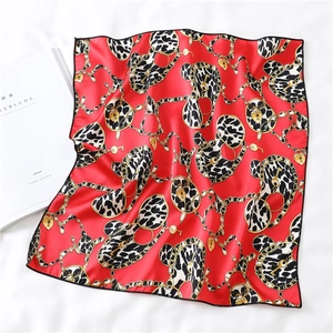 Detail showing red silk scarf with leopard hearts and gold chain print on bed