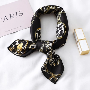 Detail of elegant black and gold silk square scarf with chain heart and leopard pattern