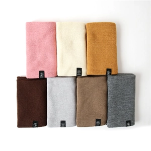 Detailed flat lay of knitted winter neck warmers in seven colors with woven brand labels