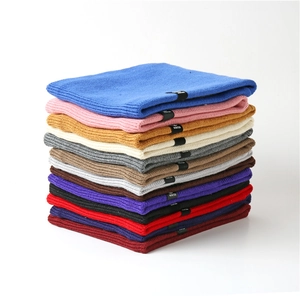 Close-up of ribbed knit winter neck warmers in multiple colors with woven brand labels