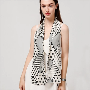 Dettaglio di un foulard sottile in seta beige con pois neri e motivi geometrici eleganti