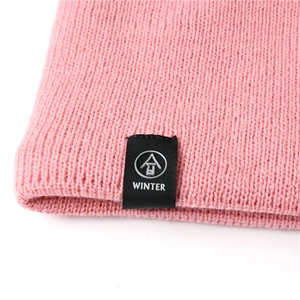 Close-up of pink knit scarf texture with a black winter label and thick woven details