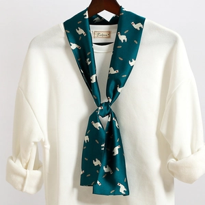Dettaglio di un foulard di seta verde scuro con stampa alpaca annodato su un maglione