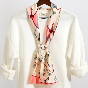 Dettaglio di un foulard in seta vintage con motivi a chiavi e bordi rosa corallo