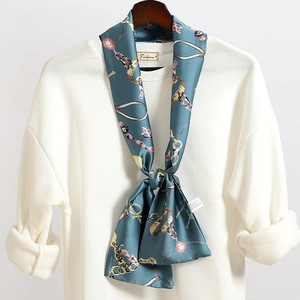 Dettaglio di un foulard in seta blu vintage con stampa a catena d'oro su una maglia