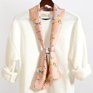 Dettaglio di un foulard in raso rosa con stampa a catena su una felpa bianca