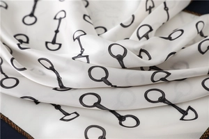 Close-up of silk scarf with equestrian horsebit print and elegant gold chain border