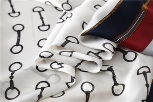 Detailed view of the smooth equestrian horse-bit pattern on the glossy silk square scarf