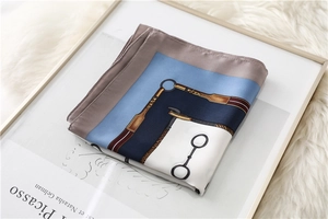 Detail of equestrian print silk scarf with bridle and stirrup patterns on plush background