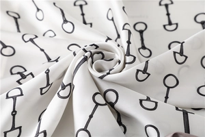 Macro shot of silk scarf fabric featuring black horsebit print on ivory background