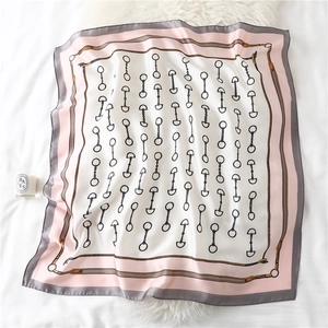 Detailed view of square silk scarf featuring classic horse bit print and pink grey borders