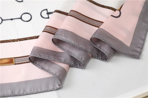 Detail of pink and white silk scarf showing equestrian patterns and satin texture