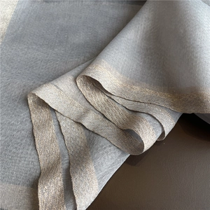 Detailed shot of grey silk-wool scarf texture with shimmering gold thread borders