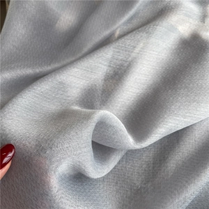 Macro shot of light gray blue silk scarf fabric showing semi-transparent texture