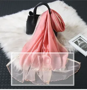 Close-up of pink scarf with golden silk edge and pearl bead detailing on fabric