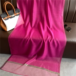 Detail of fuchsia silk blend scarf with elegant gold metallic stitched edges on leather