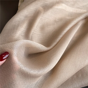Macro detail of champagne gold silk scarf fabric with shimmer texture and sheer finish