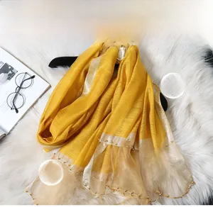 Detail of ginger silk scarf featuring hand-stitched gold beads and translucent mesh edge
