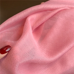 Detail of light pink silk scarf fabric showing fine texture held by fingers