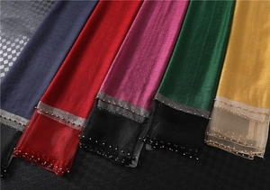 Detailed close-up of silk scarves with elegant beadwork and sheer mesh stitching
