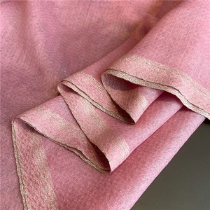 Detailed close-up of pink silk scarf showing golden embroidered geometric edges