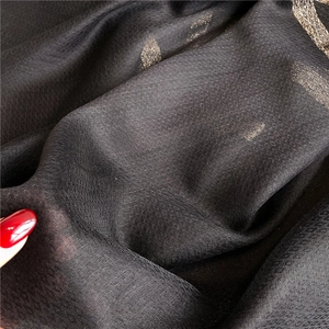 Detail showing sheer black fabric with gold leaf pattern and lightweight breathable texture