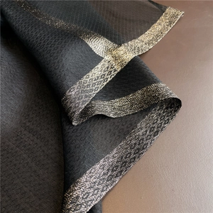 Detail of black silk wool scarf featuring geometric jacquard and luxury gold lurex border