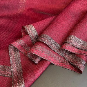 Detail of dark red scarf fabric showing gold metallic jacquard edge and fine texture