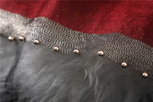 Detail of red jacquard and grey silk patchwork with silver bead and wavy trim accents
