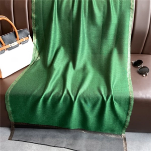 Detail of emerald green satin scarf featuring gold glitter edges and black mesh hem trim