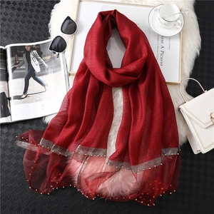 Elegant deep red silk wool scarf with mesh edges and pearl beads on a luxury background